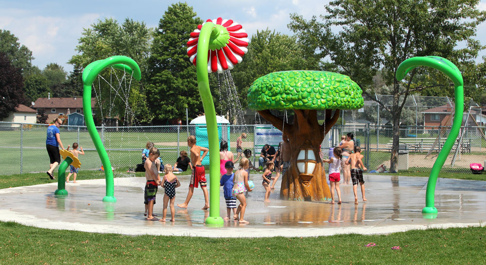 Kids playing at the Parkdale Playground splash pad with nature themes spray features